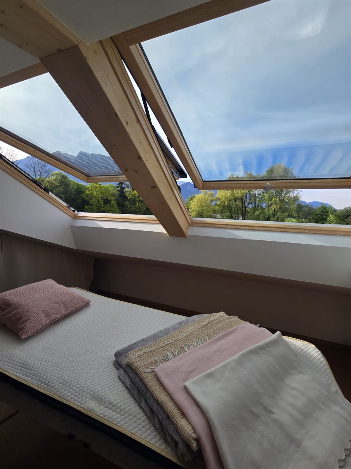 Dachstudio mit geöffneten Fenstern und Blick auf Berge und Wald
