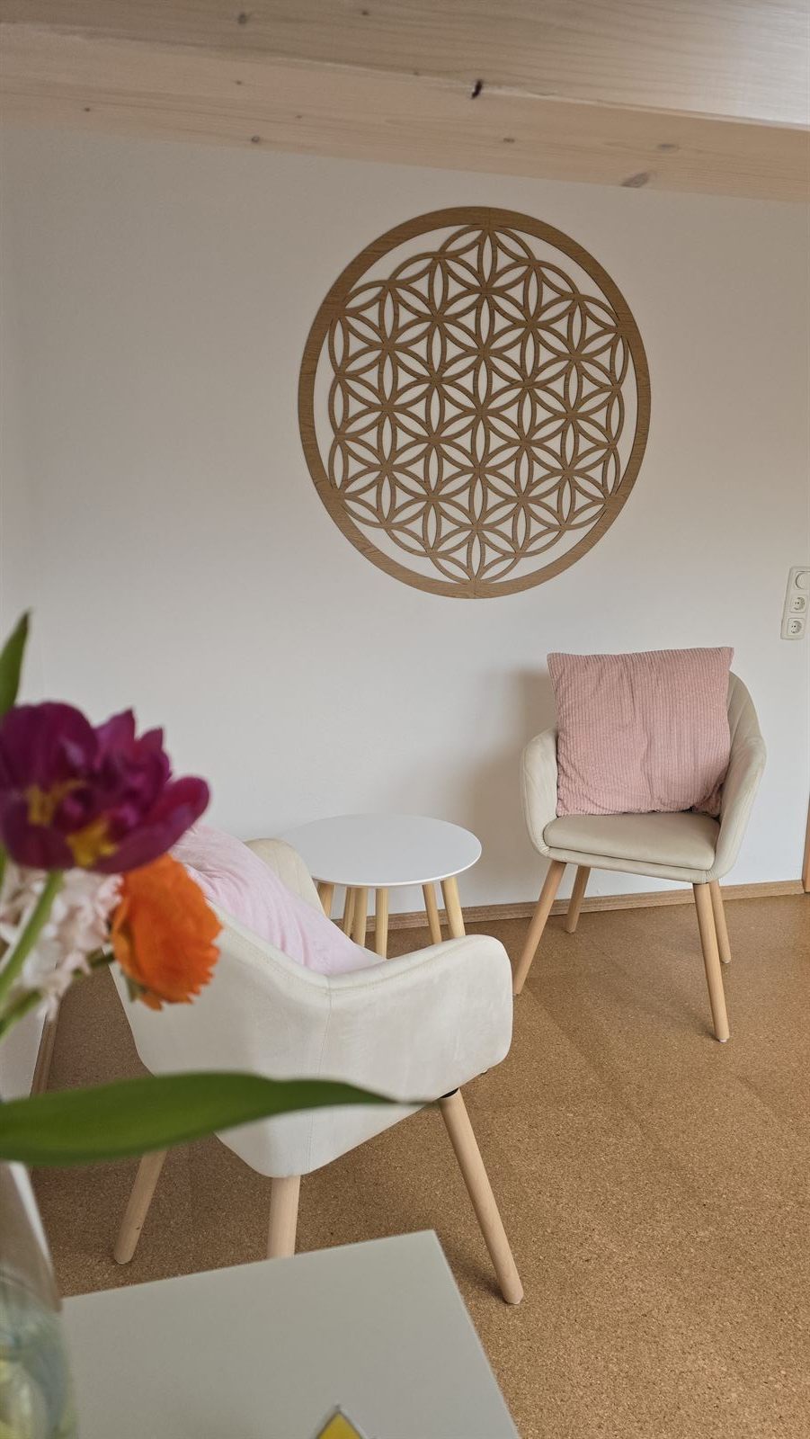 Die Blume des Lebens an der Wand im Studio mit Sessel und Blumen